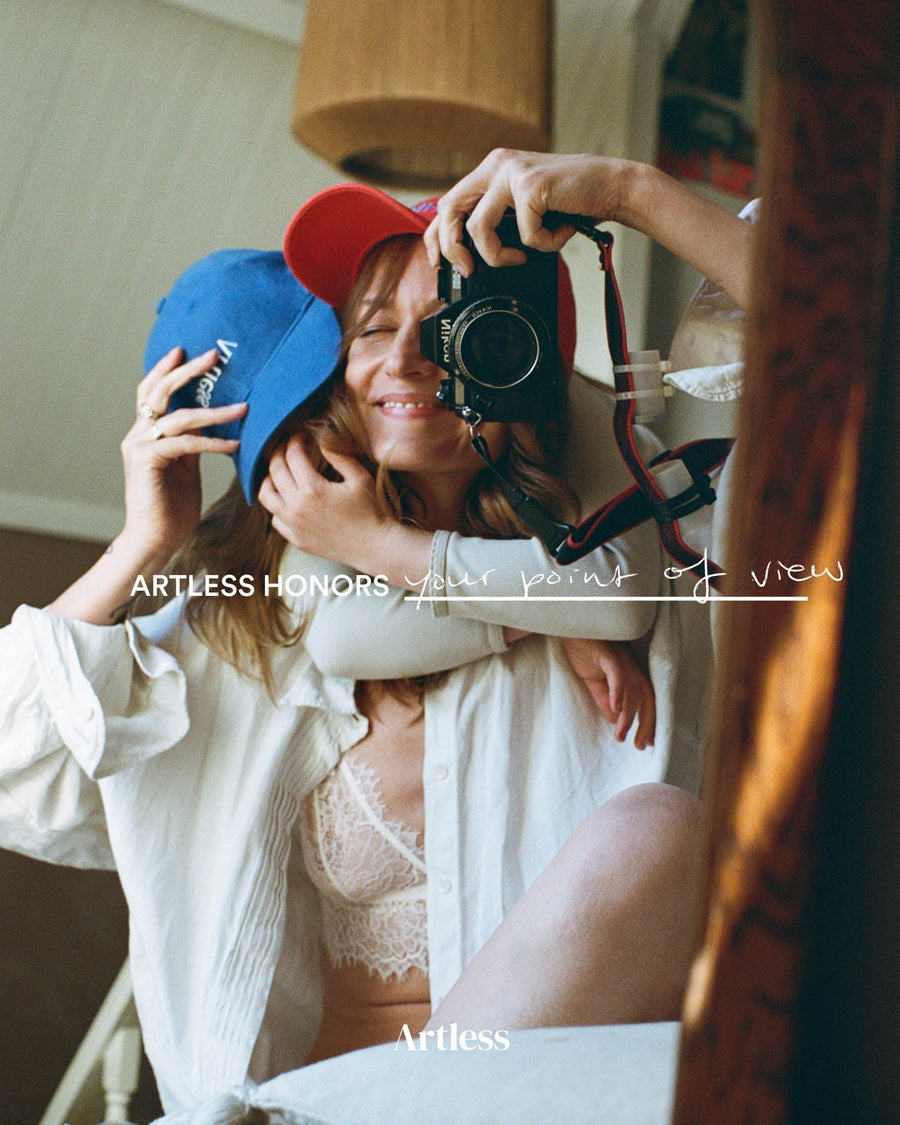 Woman and child photographing themselves in a mirror with a vintage camera, both wearing Artless organic cotton dad caps