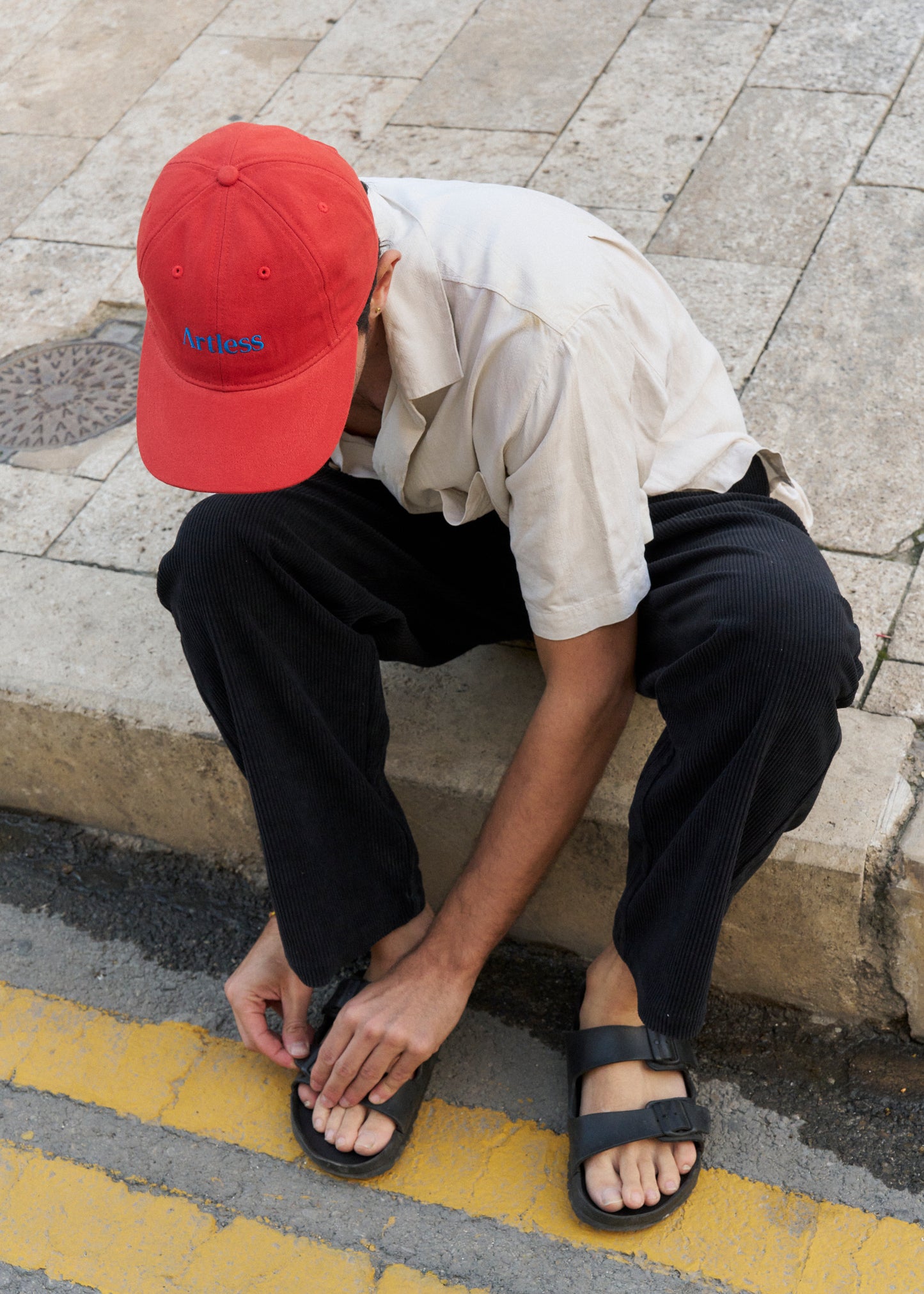 Artless red cap with blue text worn on model