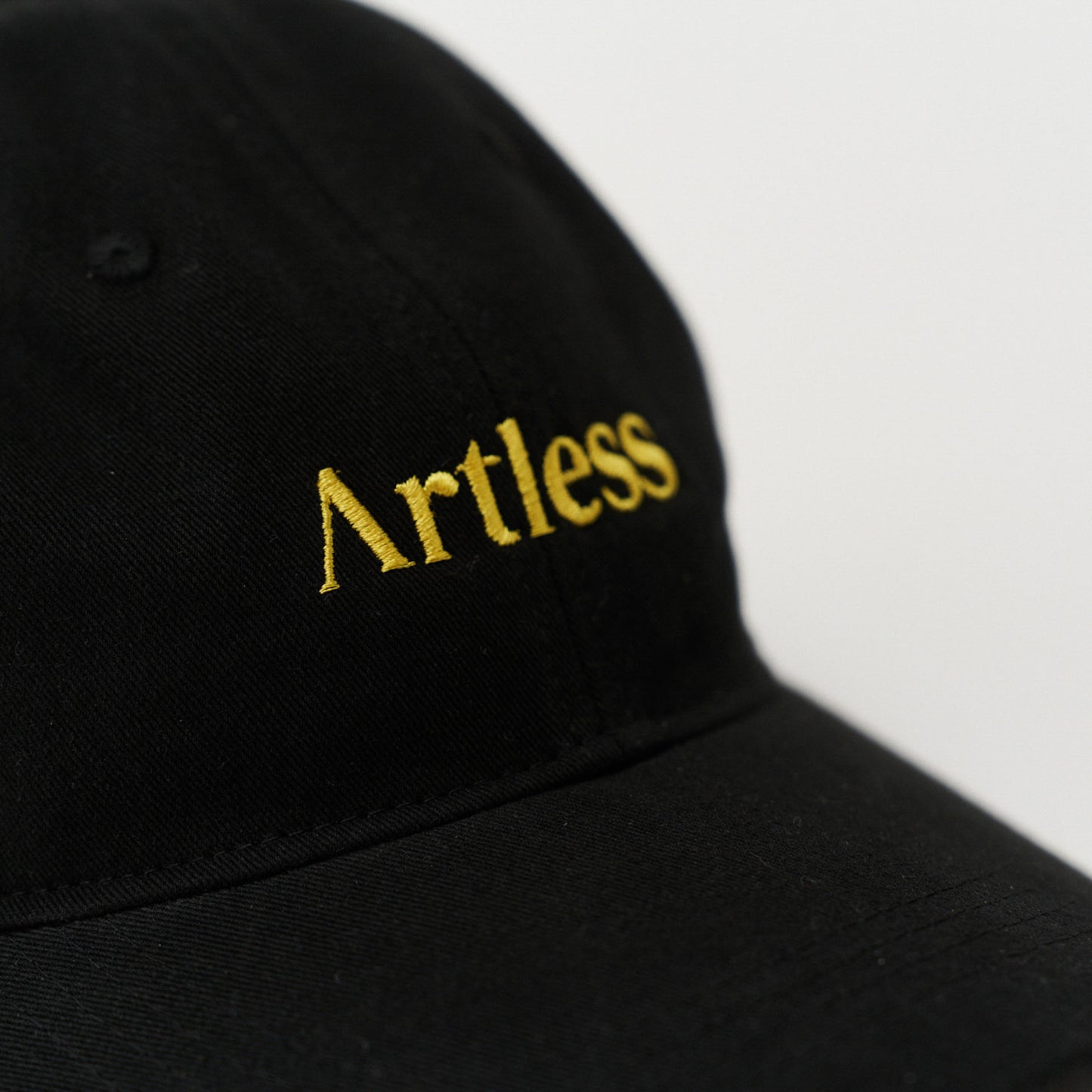 Close up of the embroidery of a black unstructured 6-panel dad cap made from GOTS certified organic cotton by Artless