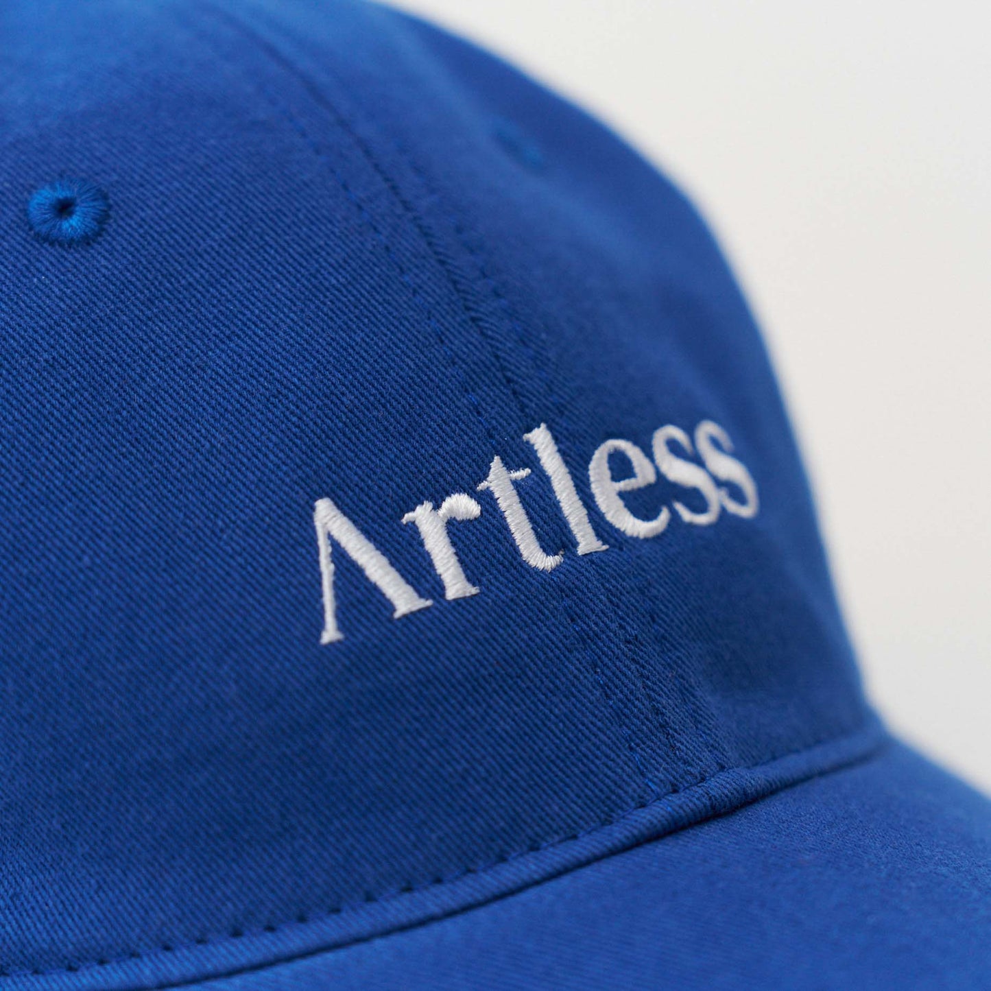 Close up of the embroidery of a blue unstructured 6-panel dad cap made from GOTS certified organic cotton by Artless
