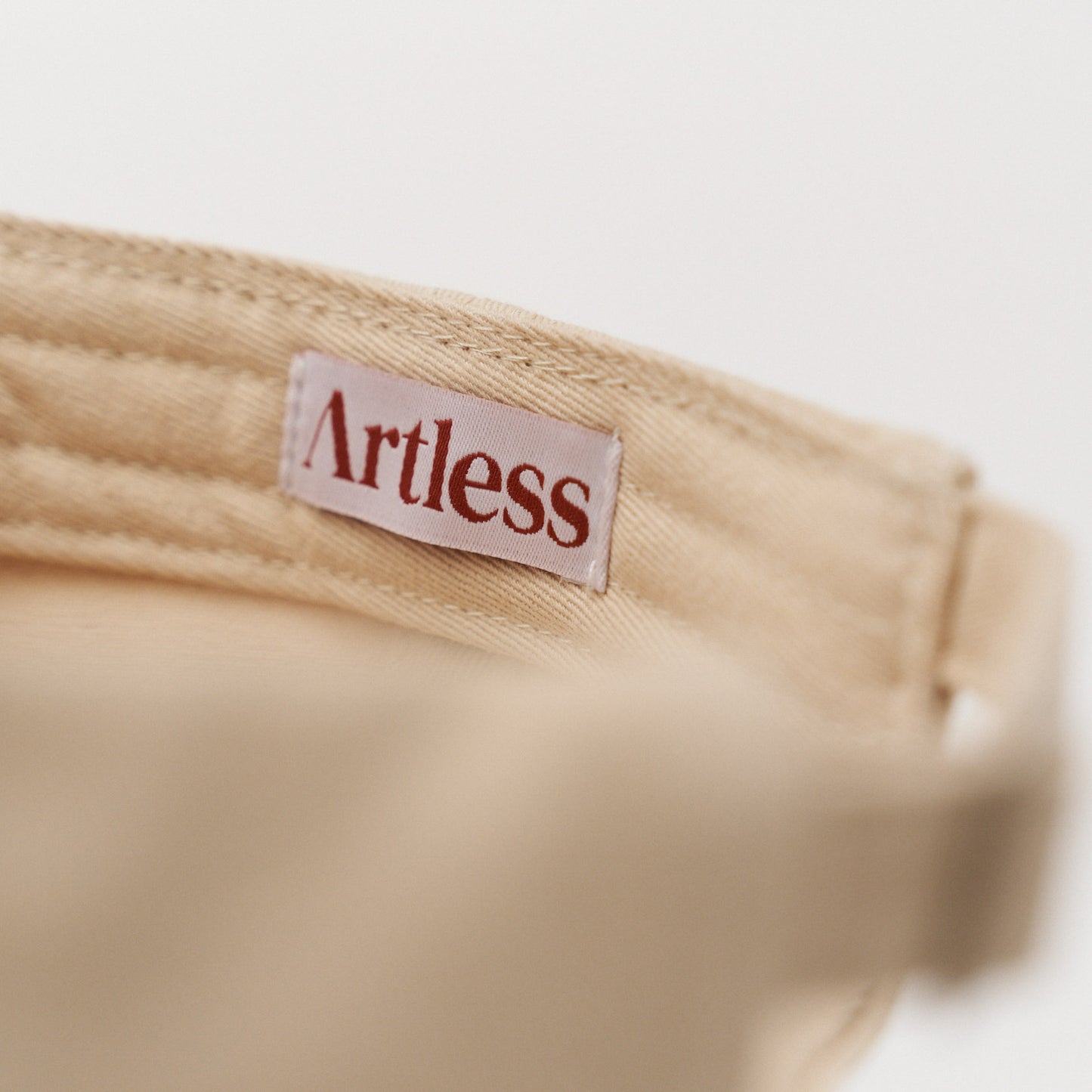 artless label inside a sand coloured unstructured 6-panel dad cap made from GOTS certified organic cotton