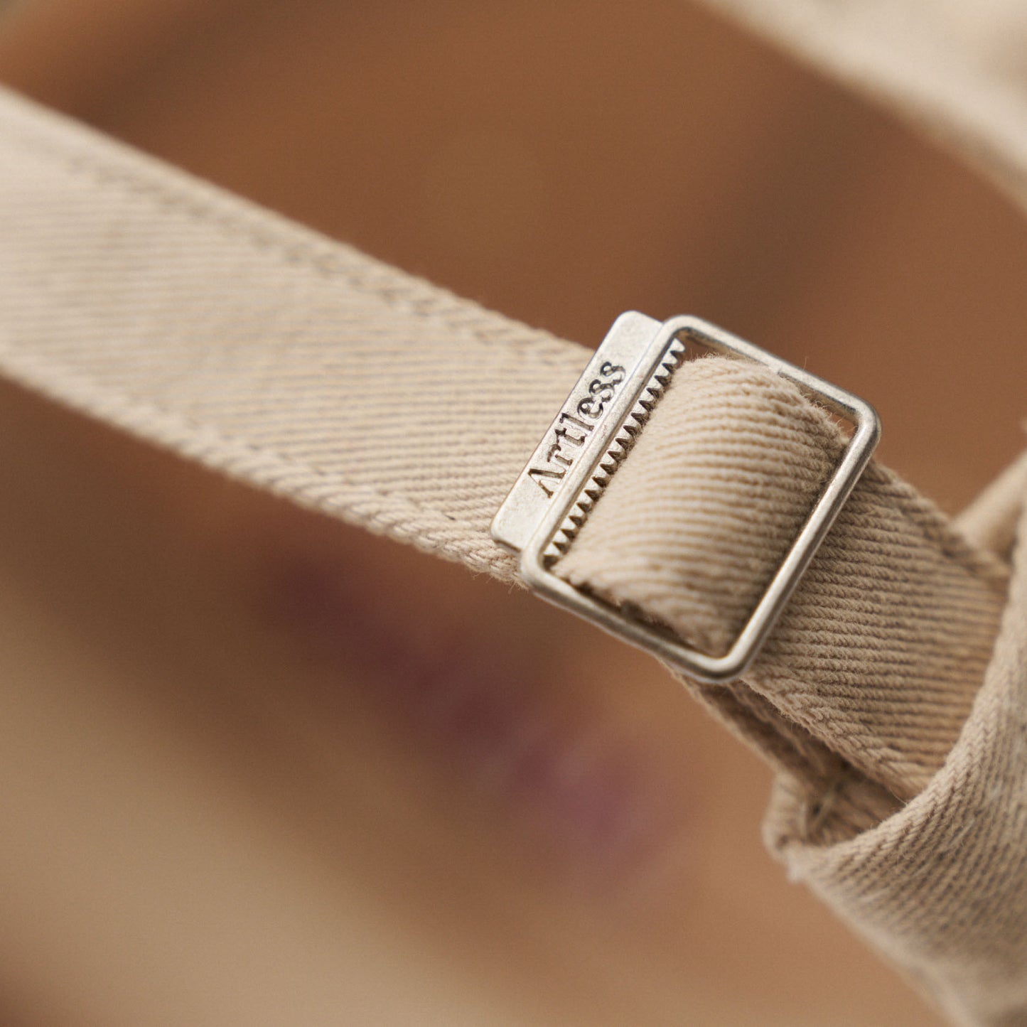 Close up of a artless engraved back buckle of the sand coloured unstructured 6-panel dad cap made from GOTS certified organic cotton by Artless