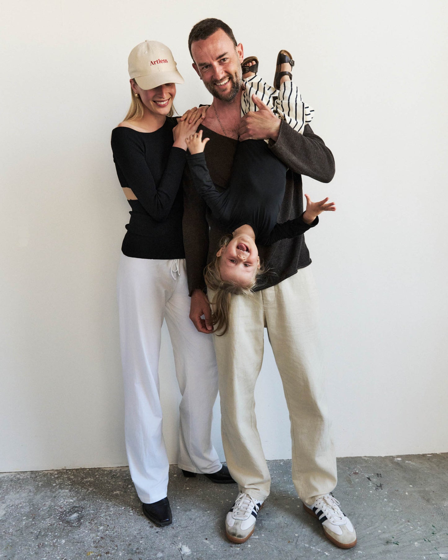 Family of three posing together having fun with their child. the woman is wearing a sand coloured GOTS organic artless dad cap