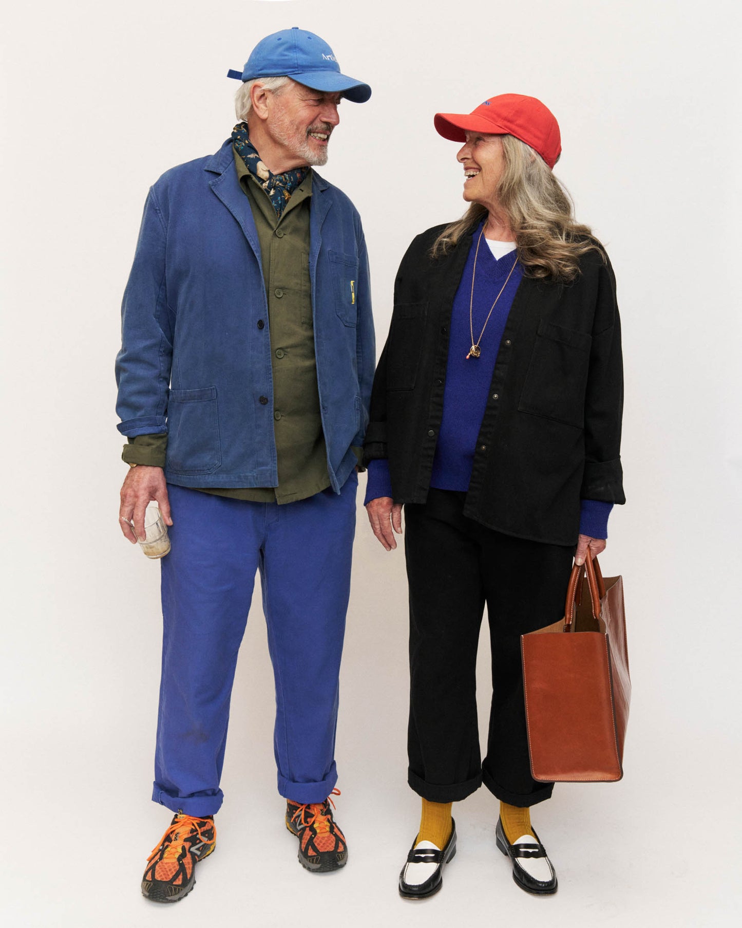 middle ages couple wearing blue and red unstructured 6-panel dad caps made from GOTS certified organic cotton by Artless artless while laughing at each other