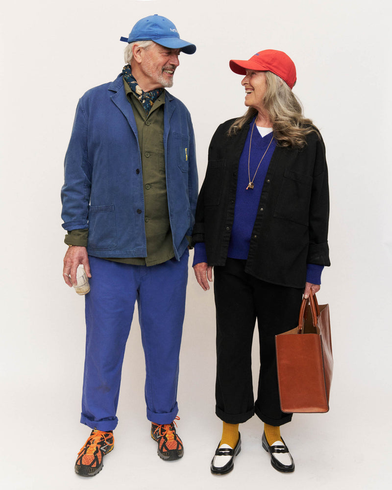 Middle-aged couple laughing together wearing blue and red unstructured 6-panel dad caps made from GOTS certified organic cotton by Artless
