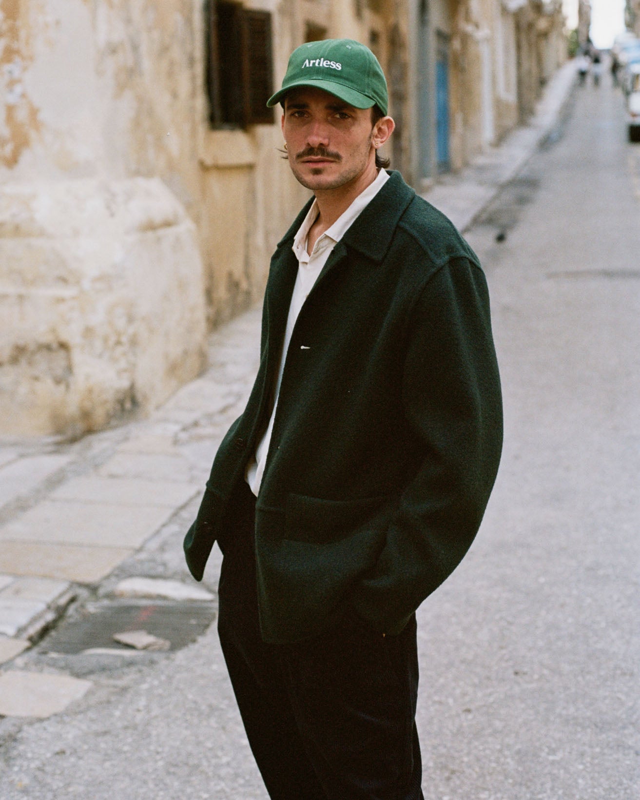 Man wearing a green coat and green unstructured 6-panel dad cap made from GOTS certified organic cotton by Artless