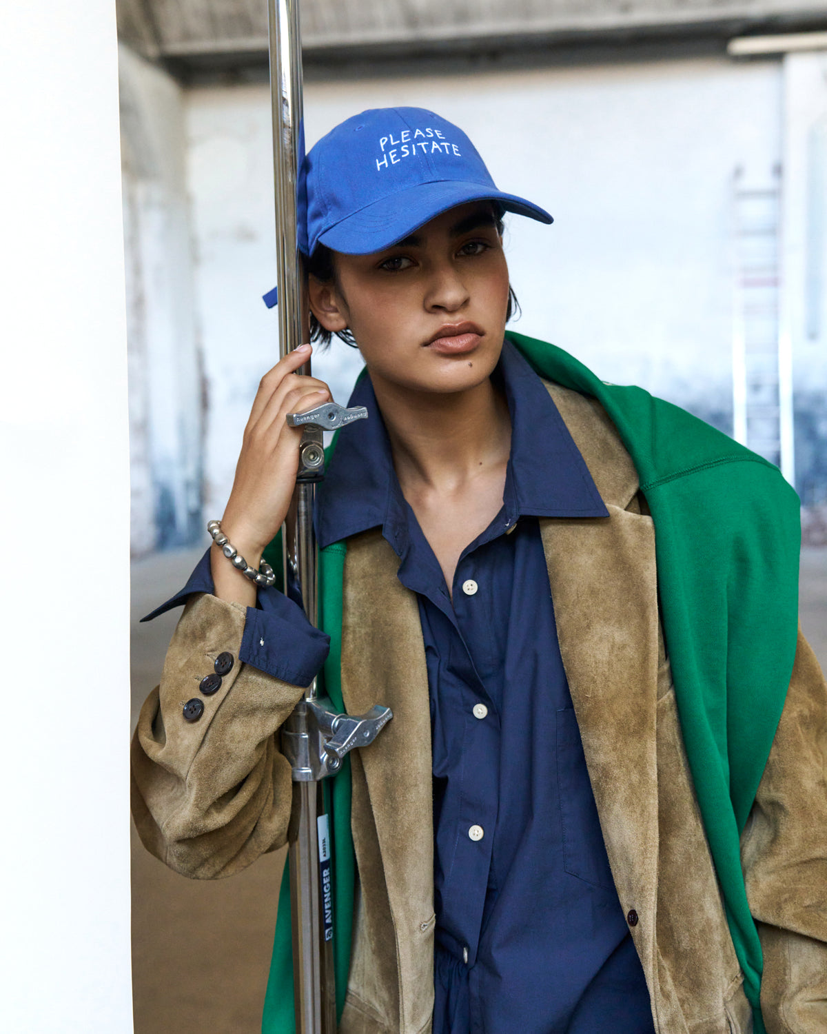 Person on the phone wearing the blue Artless Please Hesitate organic cotton dad cap, navy shirt and green and tan jacket