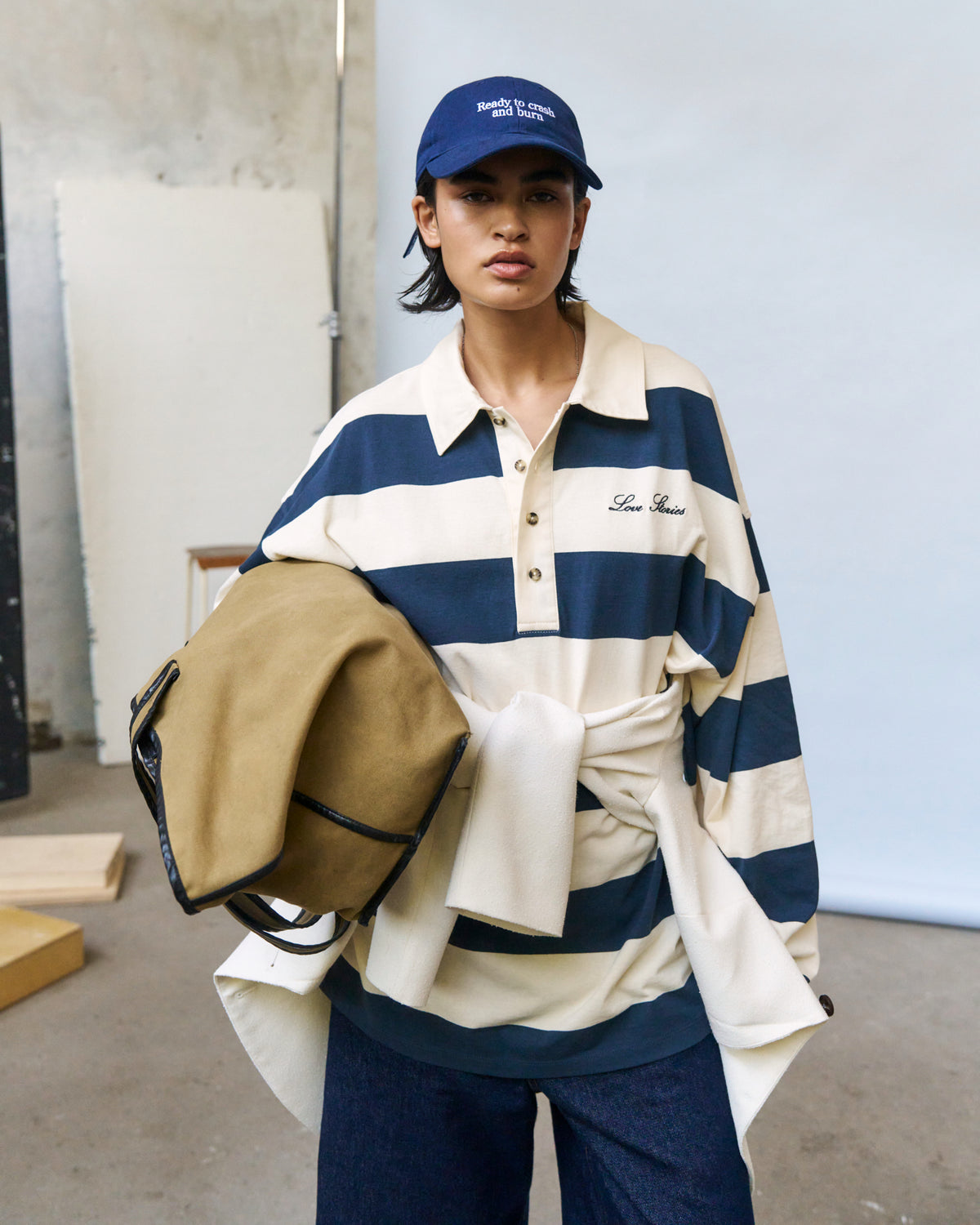 Woman wearing the navy Artless Ready To Crash And Burn organic cotton dad cap, cream and navy striped rugby shirt and tan jacket