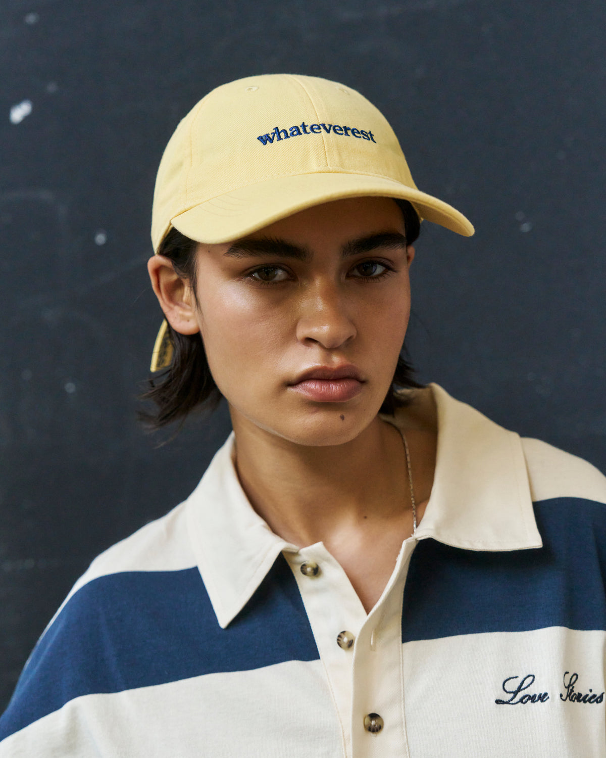Portrait of a young man wearing the butter yellow Artless Whateverest organic cotton dad cap and a cream and navy rugby polo