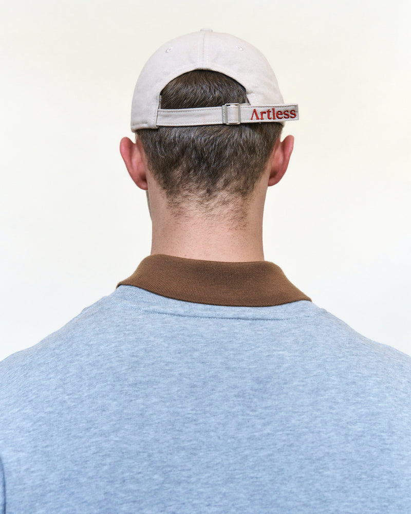 Back view of a man wearing the sand Artless You Barely Live Once organic cotton dad cap with the embroidered Artless strap and a grey sweater