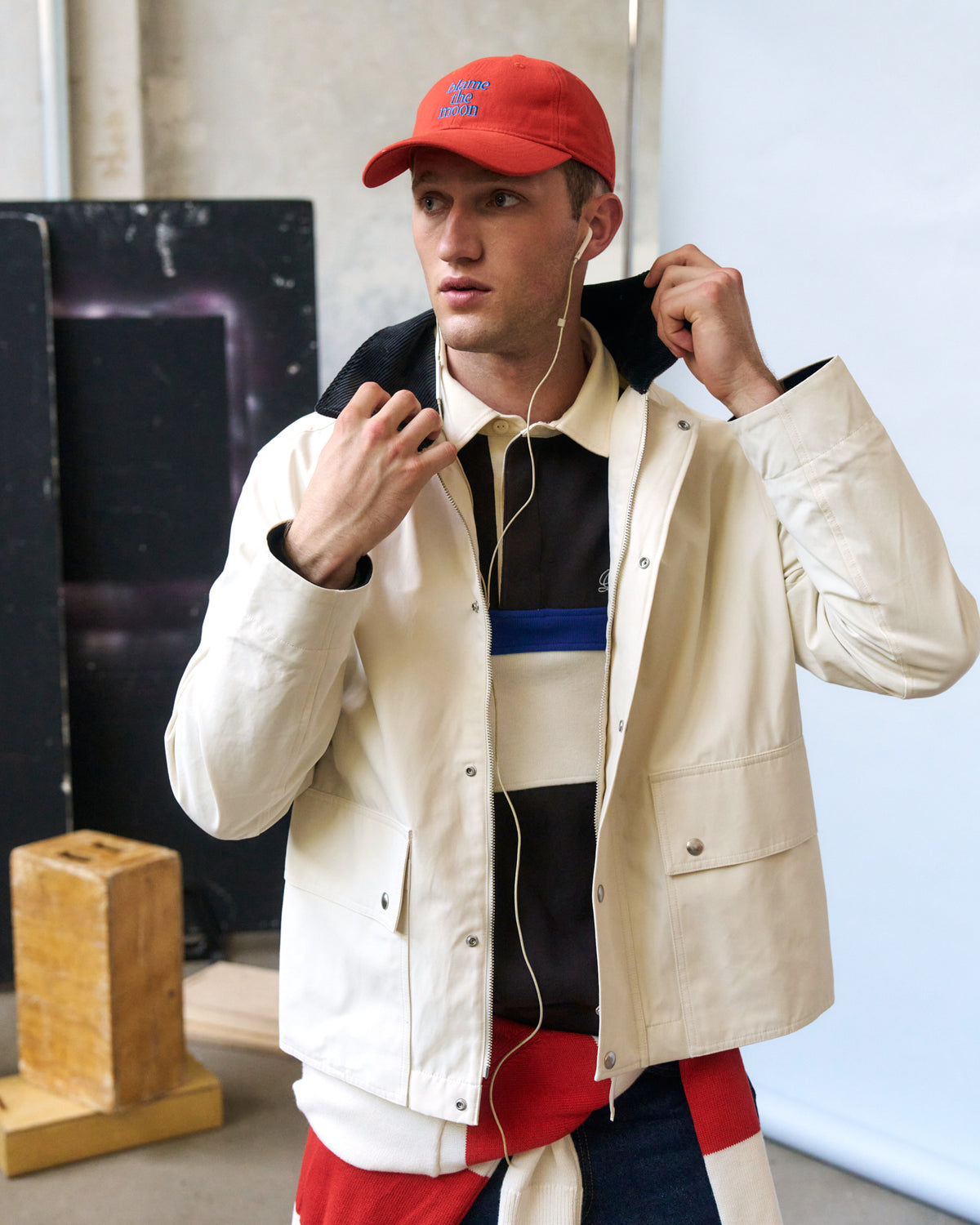 Man wearing the red Artless Blame the Moon organic cotton dad cap and a cream colour block jacket in a studio