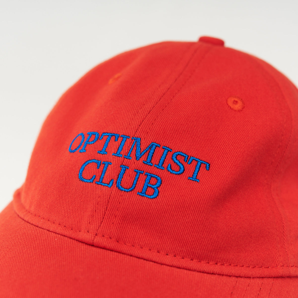 Red Artless Optimist Club organic dad cap with blue embroidery, front view, unstructured 6-panel GOTS organic cotton