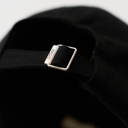 Close up of a artless engraved back buckle of the black unstructured 6-panel dad cap made from GOTS certified organic cotton by Artless