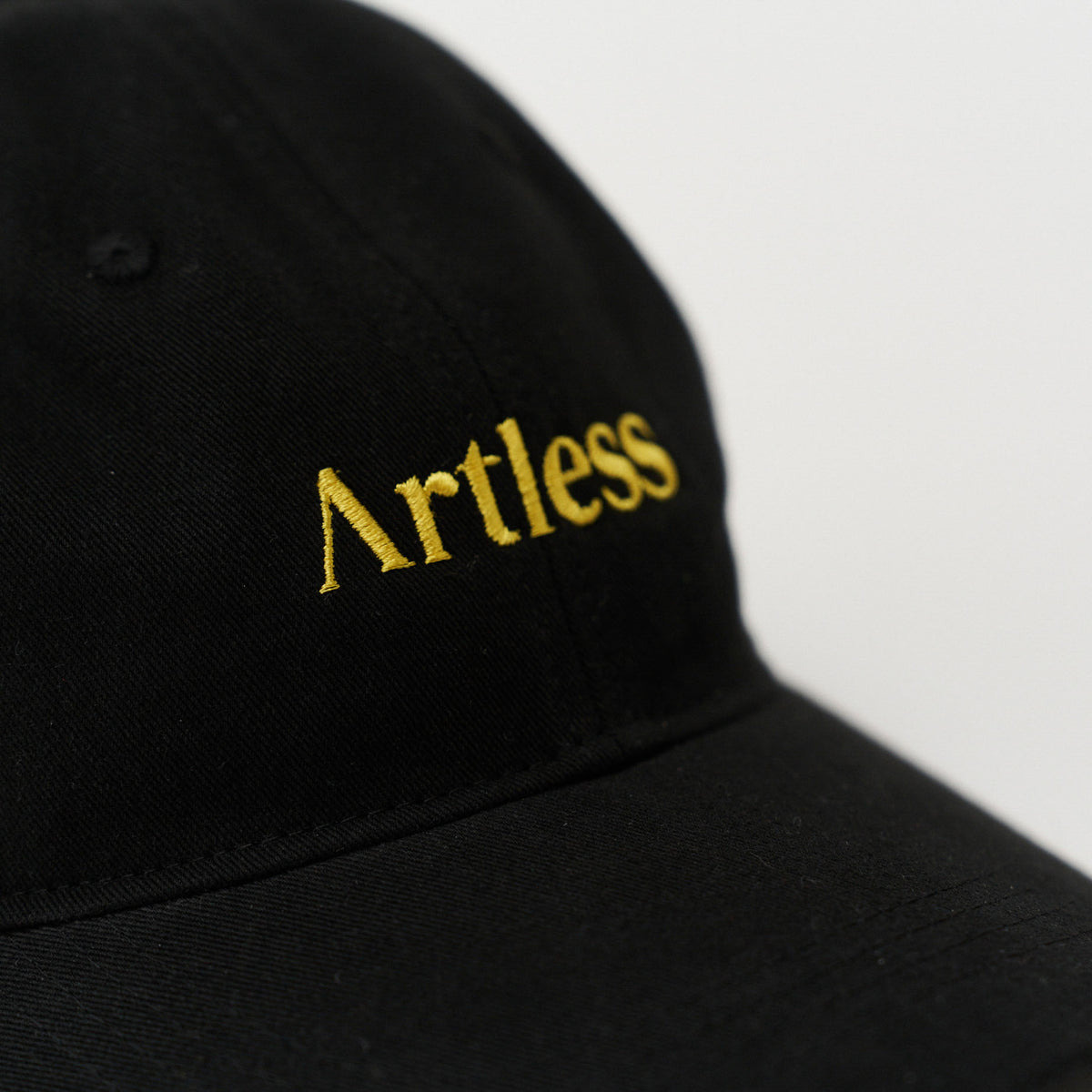 Close up of the embroidery of a black unstructured 6-panel dad cap made from GOTS certified organic cotton by Artless