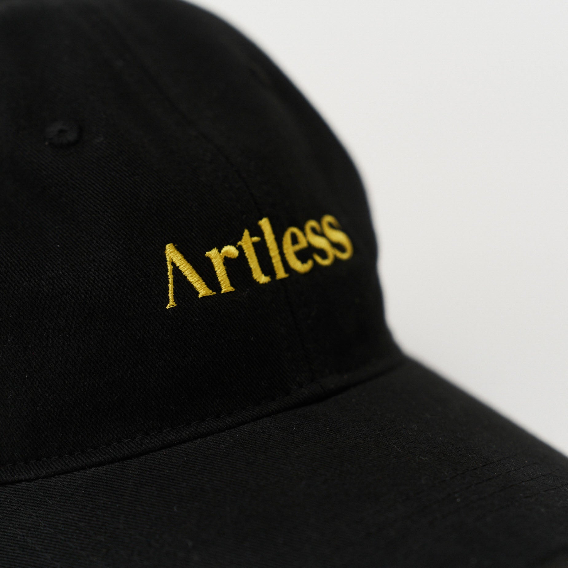 Close up of the embroidery of a black unstructured 6-panel dad cap made from GOTS certified organic cotton by Artless