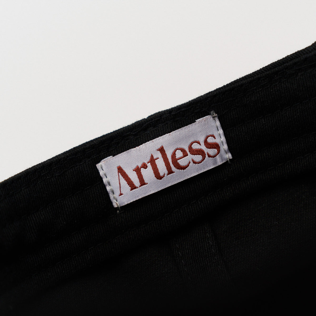 Artless label inside a black unstructured 6-panel dad cap made from GOTS certified organic cotton