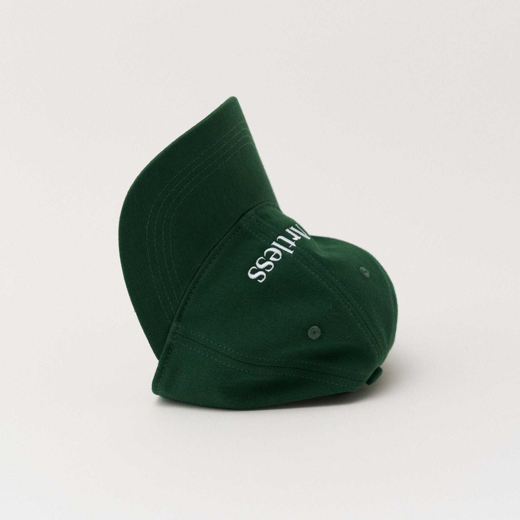Green unstructured 6-panel dad cap made from GOTS certified organic cotton by Artless tipped on it's side