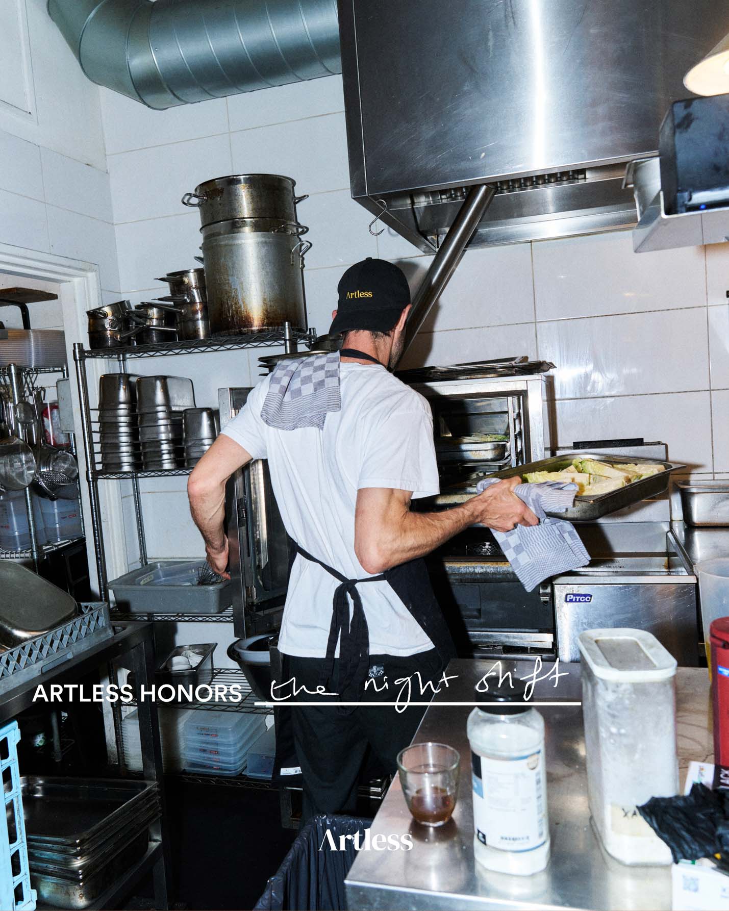 Person working in a kitchen with equipment wearing a black unstructured 6-panel dad cap made from GOTS certified organic cotton by Artless
