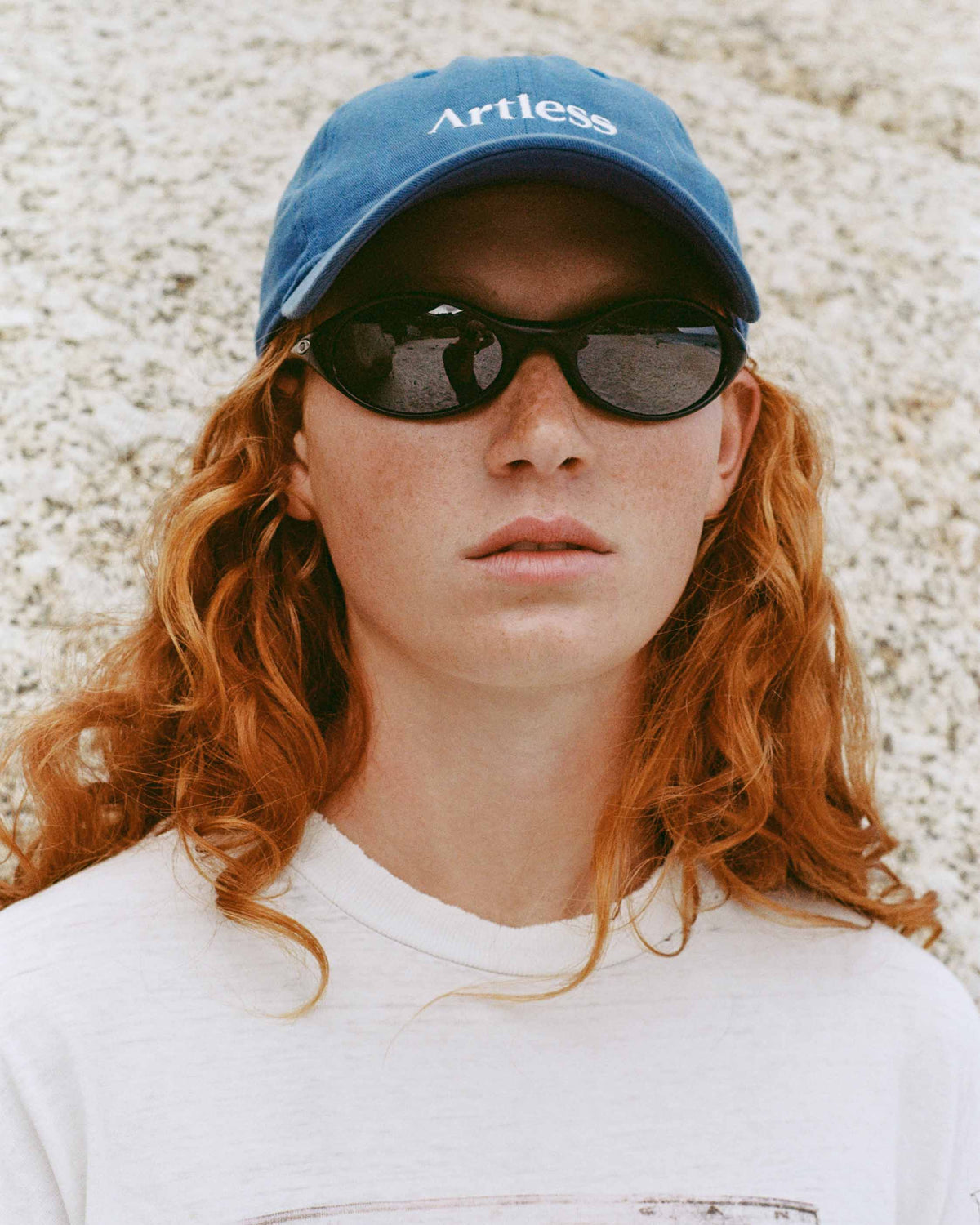 woman with vintage oakley sunglasses wearing a blue unstructured 6-panel dad cap made from GOTS certified organic cotton by Artless 