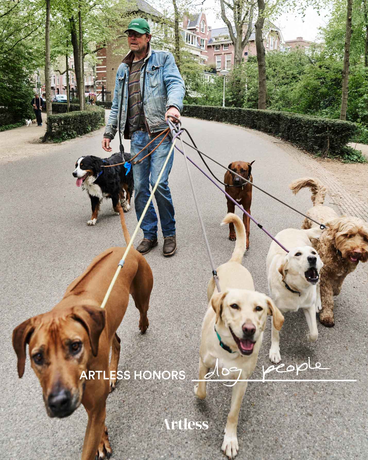 Man walking multiple dogs on a city street with a green unstructured 6-panel dad cap made from GOTS certified organic cotton by Artless