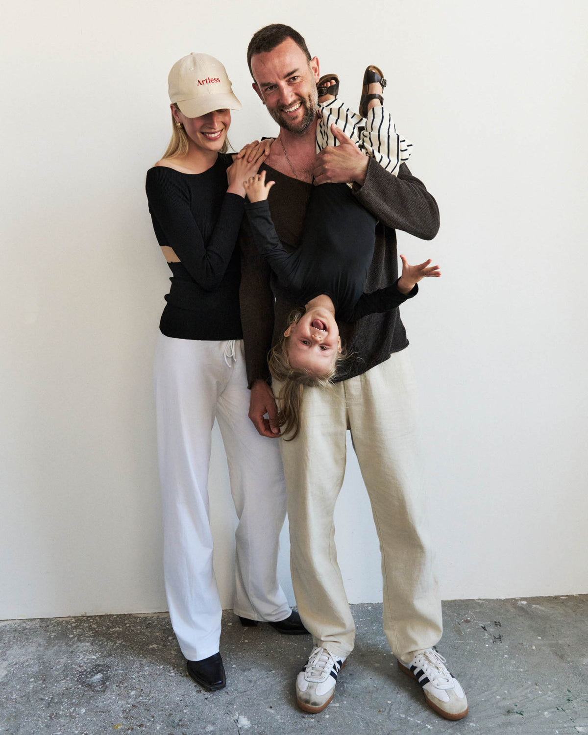 Family of three posing together having fun with their child. the woman is wearing a sand coloured GOTS organic artless dad cap