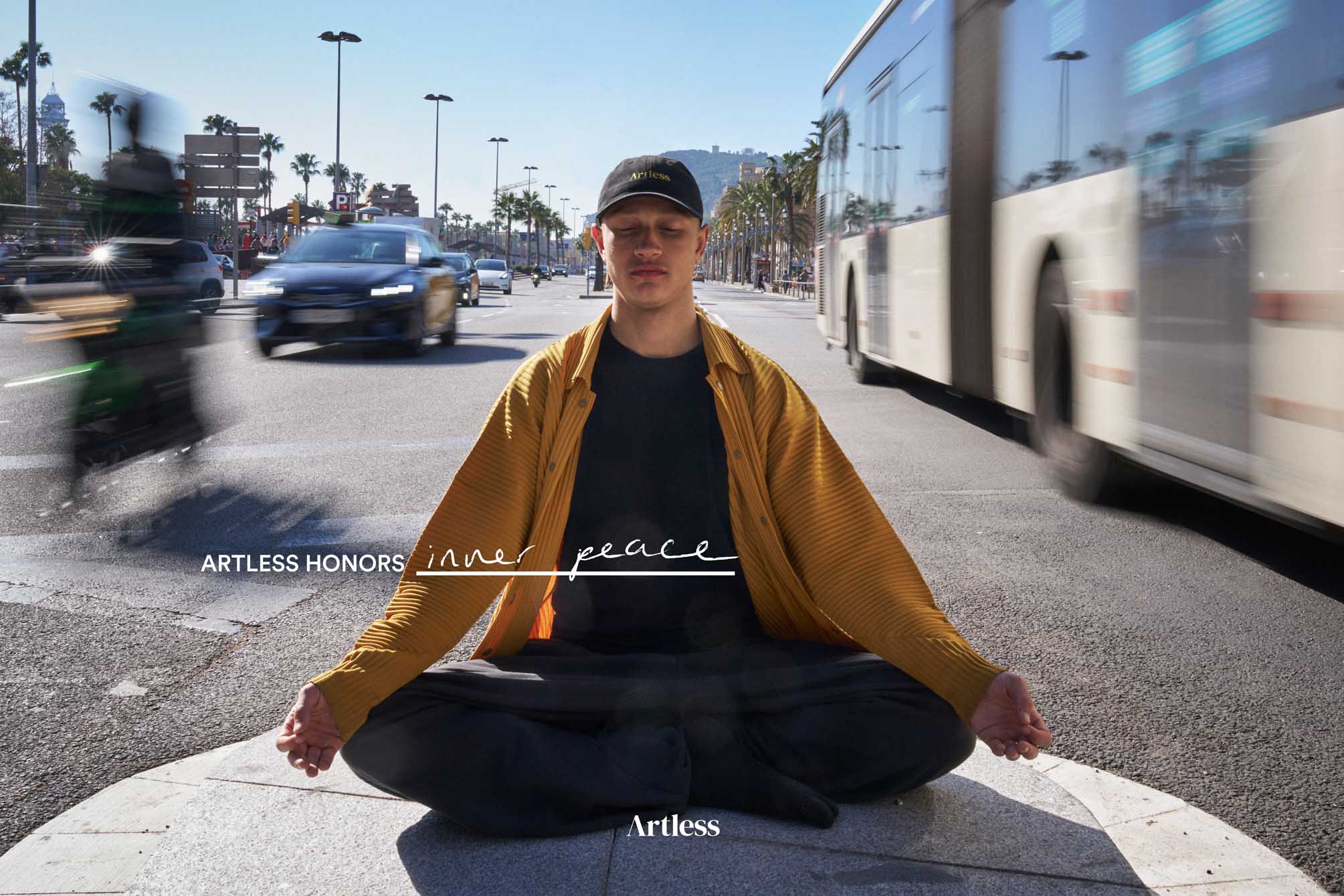 Person sitting on a street meditating wearing a black unstructured 6-panel dad cap made from GOTS certified organic cotton by Artless