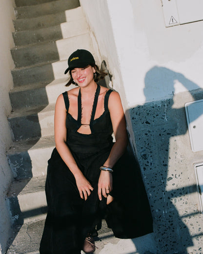 woman laughing in the sun wearing a black Close up of the embroidery of a green unstructured 6-panel dad cap made from GOTS certified organic cotton by Artless