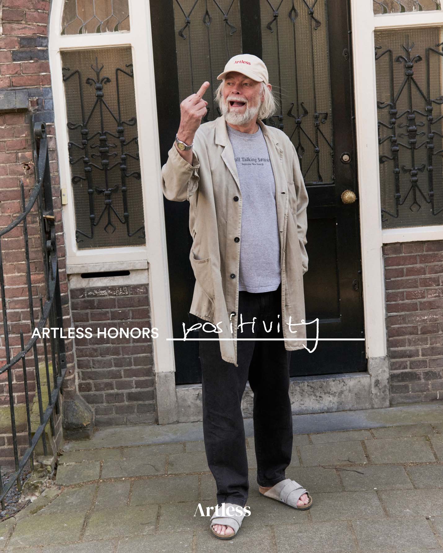 Man standing outside a building giving the middle finger wearing a sand coloured unstructured 6-panel dad cap made from GOTS certified organic cotton by Artless