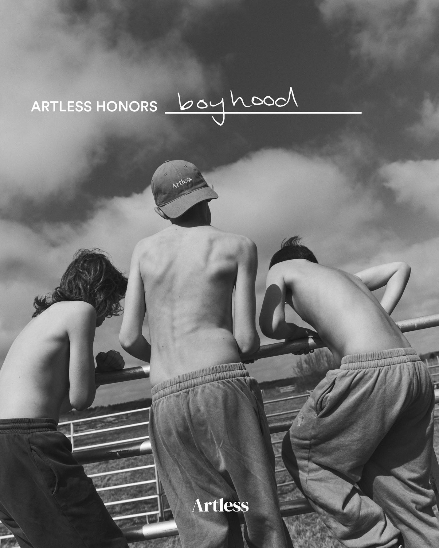 Black and white photo of three boys climbing a fence while one wears a unstructured 6-panel dad cap made from GOTS certified organic cotton by Artless