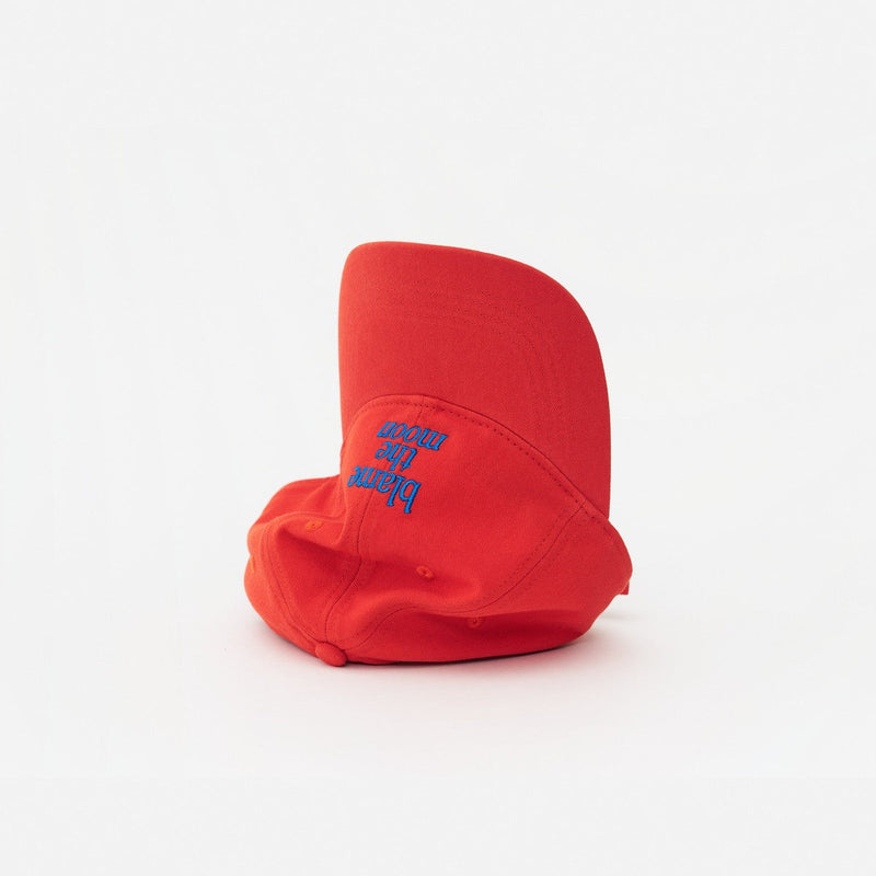 Red Artless Blame the Moon organic dad cap, laying on its side