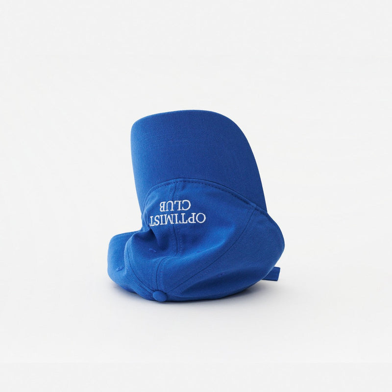 Blue Artless Optimist Club organic dad cap, laying on its side