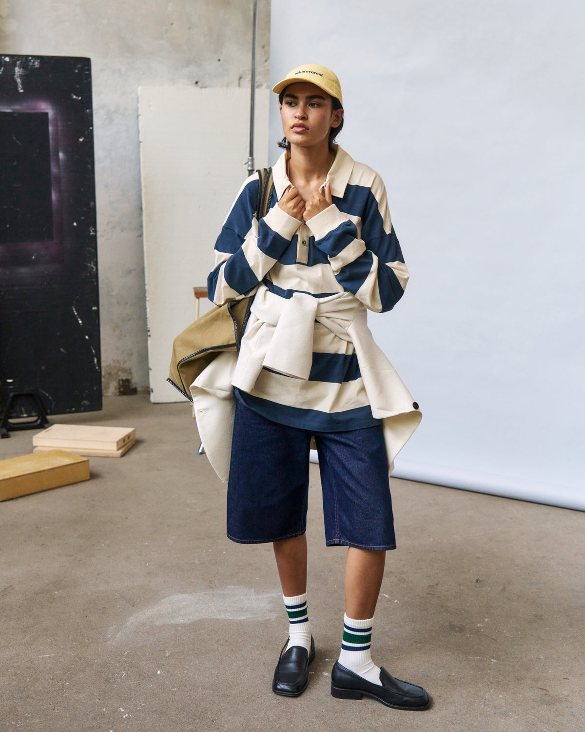 Person wearing the butter yellow Artless Whateverest organic cotton dad cap, cream and navy striped jacket and navy shorts