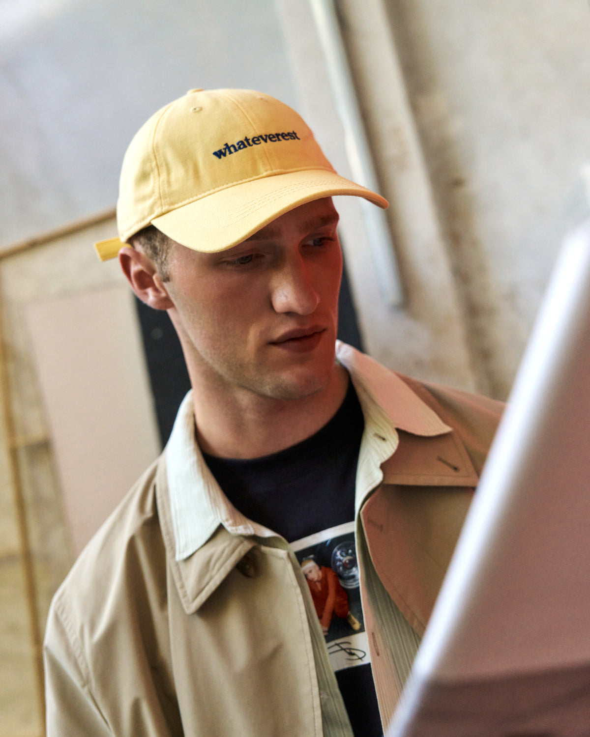 Portrait of a man wearing the butter yellow Artless Whateverest organic cotton dad cap with a tan jacket over a black t-shirt